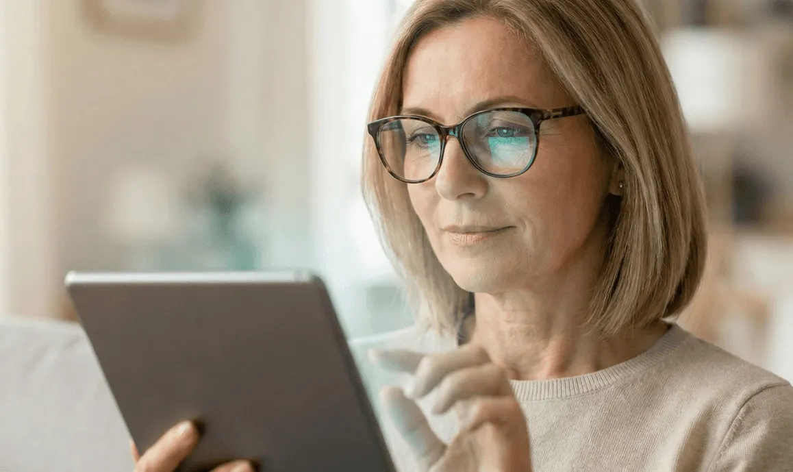 A woman wearing glasses takes a memory test on a tablet.